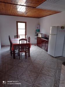 cocina con mesa, sillas y nevera en Casa Recanto en Campos do Jordão