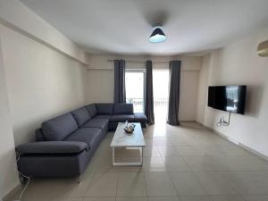 ein Wohnzimmer mit einem blauen Sofa und einem TV in der Unterkunft Greek Harmony Apartment in Paralimni