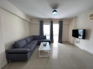 a living room with a blue couch and a tv at Greek Harmony Apartment in Paralimni
