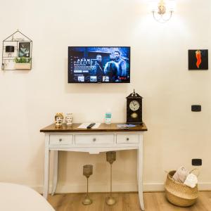 a tv on a wall above a table with a clock at Residenza Sforza Apartment 1 in Naples