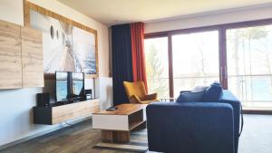 a living room with a blue couch and a tv at Stacja Mazury(Masuria Station) in Narty