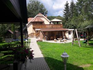 una casa con terraza y un patio con parque infantil en Szilvásvárad Camping & Apartman, en Szilvásvárad