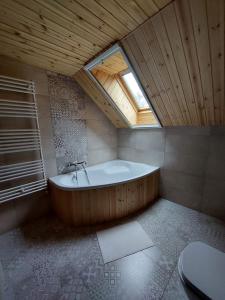 a large bathroom with a bath tub with a window at Szilvásvárad Camping & Apartman in Szilvásvárad