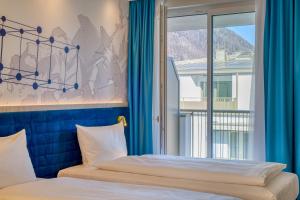 巴特莱辛哈尔ibis Styles Bad Reichenhall的一间卧室配有床和蓝色窗帘的窗户
