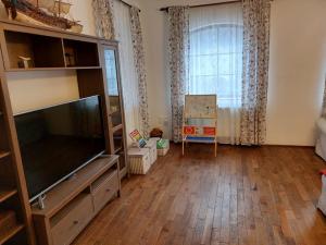 a living room with a flat screen tv and a large window at Szilvásvárad Camping & Apartman in Szilvásvárad