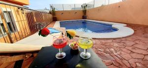 two wine glasses on a table next to a swimming pool at Villa Flor de Loto in Palazuelos