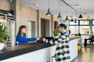 a man and a woman shaking hands at a counter at a&o Dresden Hauptbahnhof in Dresden