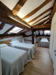 Duas camas num quarto com tectos em madeira em El Pino em Penagos