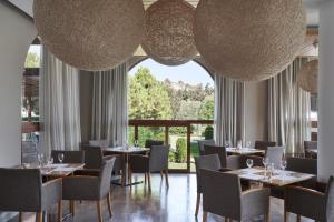 コリンビアにあるAtlantica Holiday Village Rhodesのテーブルと椅子、大きな照明が備わるレストラン