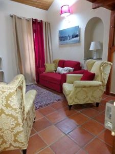 a living room with two chairs and a red couch at A Casinha da Vila in Vila Viçosa