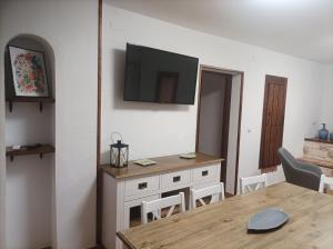 a dining room with a table and a tv on the wall at Casa La Piedra in Segura de la Sierra