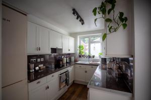 uma cozinha com armários brancos e um balcão preto em St Owen's Terrace by RentMyHouse em Hereford