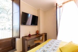 Schlafzimmer mit einem Bett, einem Schreibtisch und einem TV in der Unterkunft Santoro Country House in Castiglione di Sicilia