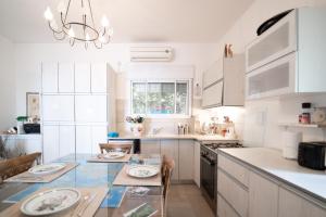 a kitchen with white cabinets and a table with plates on it at חופשה שקטה בכרמל נוף לים, שקיעות וחניה חינם in Haifa