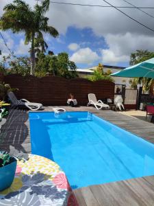 - une piscine bleue avec des chaises et un parasol dans l'établissement An ti kaz la, à Sainte-Anne