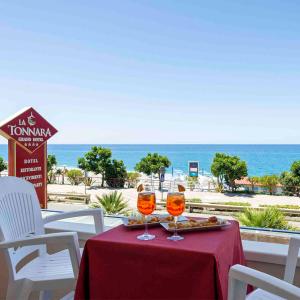 a table with two wine glasses on a table with the beach at Grand Hotel La Tonnara in Amantea