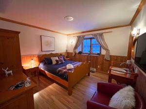 a bedroom with a bed and a chair and a tv at Auberge au Poste de Traite in Sainte-Famille
