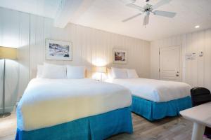 a bedroom with two beds and a ceiling fan at Riotel Perce in Perce
