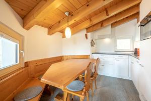 Una cocina con una mesa y sillas de madera. en Casa Darschalè 11, en Laax