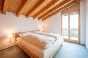 a bedroom with a bed with white sheets and a window at Casa Darschalè 11 in Laax