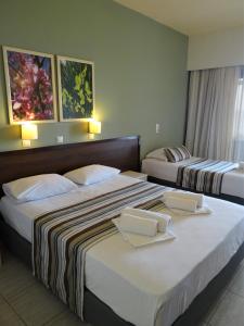 
a hotel room with two beds and two nightstands at Horizon Beach Hotel in Plakias
