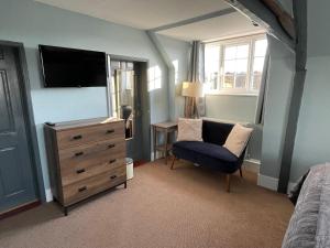 a bedroom with a tv and a chair and a dresser at Rockstone Cottage in Freshwater