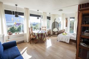 sala de estar con mesa, sillas y ventanas en Blómasetrið Homestay, en Borgarnes