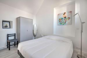 Saint-ArmelにあるGrande maison pour 8 personnes à St Armelの白いベッドと椅子のある白い寝室