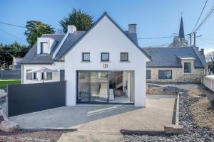 a white house with a large glass door at Grande maison pour 8 a St Armel in Saint-Armel