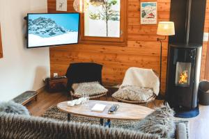 a living room with a fireplace and a table and chairs at Le Chalet des Tartalys - 750 m des pistes de Serre Chevalier Chantemerle in Saint-Chaffrey