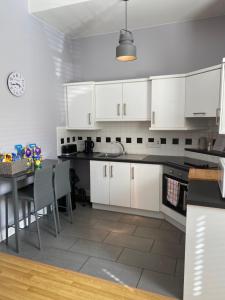 a kitchen with white cabinets and a table with chairs at Chapel View in Ballycastle