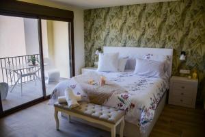 a bedroom with a large white bed with a bench at El Tossal in El Castell de Guadalest