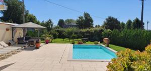 ein kleiner Pool im Garten mit Sonnenschirm in der Unterkunft House with pool CASA DA FAIA - AVEIRO (Estarreja) in Avanca