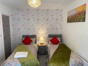 two beds in a bedroom with red and green pillows at Central Newly built 2 Bed DUPLEX Penthouse with FREE On-site Gated Parking, Lift access, Self Check-in, SUPER Fast WIFI, TWO Cathedral view Terraces & Sleeps 6 in Peterborough