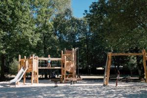 a child is playing on a wooden playground at Huttopia Lac de Sillé in Sillé-le-Guillaume