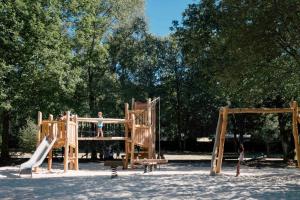 un enfant joue sur une aire de jeux en bois dans l'établissement Huttopia Lac de Sillé, à Sillé-le-Guillaume