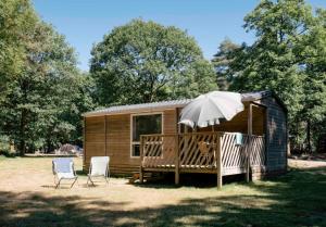 una piccola cabina con due sedie e un ombrellone di Huttopia Lac de Sillé a Sillé-le-Guillaume