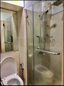 een badkamer met een toilet en een glazen douchecabine bij Grass Residences Tower 5 in Manilla
