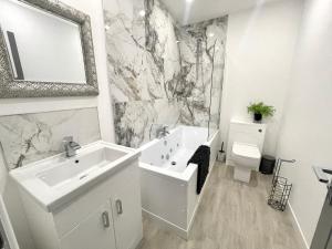 Baño blanco con lavabo y aseo en Osborne luxury hot tub and jacuzzi suites, en Blackpool