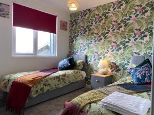 um quarto com 2 camas e papel de parede floral em Central 2 bed Newly built DUPLEX Penthouse with FREE Gated, On-site Parking, Lift access, Self Check-in, SUPER Fast WIFI, TWO Cathedral view Terraces & Sleeps 6 em Peterborough