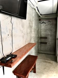 a wooden bench with a television on a wall at Frog Beach House in Ko Phayam