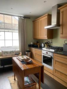 a kitchen with wooden cabinets and a wooden table with a table sidx sidx at Comfortable 2 Bedroom Apartment in Lavish Holland Park with Balcony in London