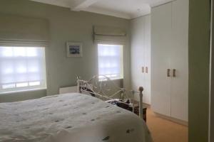 a bedroom with a bed and two windows at Comfortable 2 Bedroom Apartment in Lavish Holland Park with Balcony in London