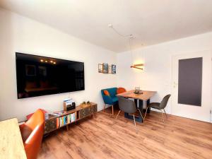 a living room with a tv and a table and chairs at Predigtstuhlblick Apartment - Terrasse - Pool - Panorama in Bad Reichenhall