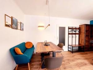 a dining room with a blue couch and a wooden table at Predigtstuhlblick Apartment - Terrasse - Pool - Panorama in Bad Reichenhall