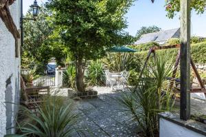 a garden with a table and chairs and a tree at The Loft - 1 Bedroom Apartment - Saint Florence, Tenby in Saint Florence