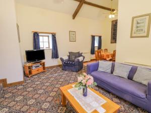 sala de estar con sofá púrpura y mesa en Wheelhouse Cottage, en Whitby