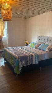a bedroom with a large bed with a blanket on it at Casa Retro Acacias Hostel in Acacías
