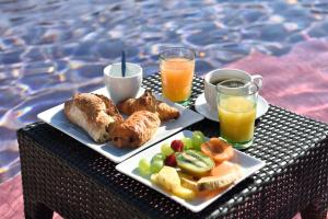 une table avec deux assiettes de nourriture et deux verres de jus d'orange dans l'établissement Le Jardin de Babylone "réservé aux couples", au Cap d'Agde