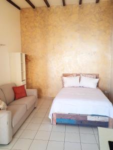 a bedroom with a bed and a couch at Studio élégant à Baie Mahault de 19 m² avec balcon et parking in Baie-Mahault